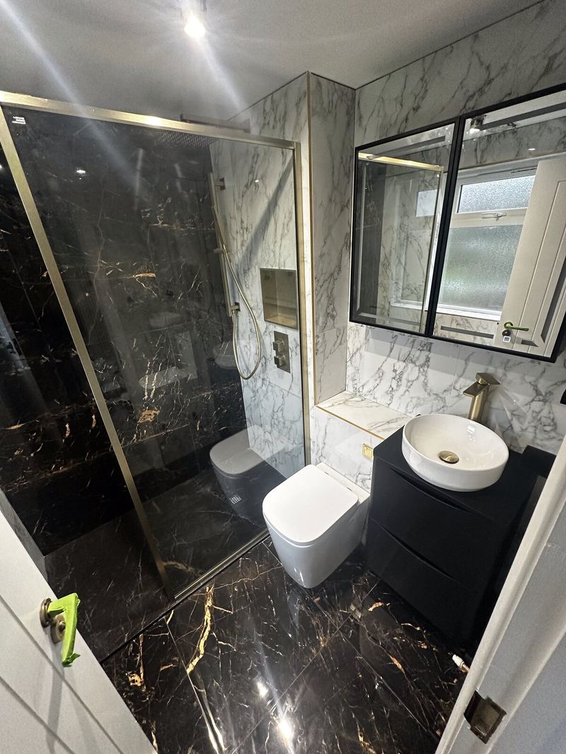 Black and gold marble-effect ensuite with brass shower screen and white marble-effect walls