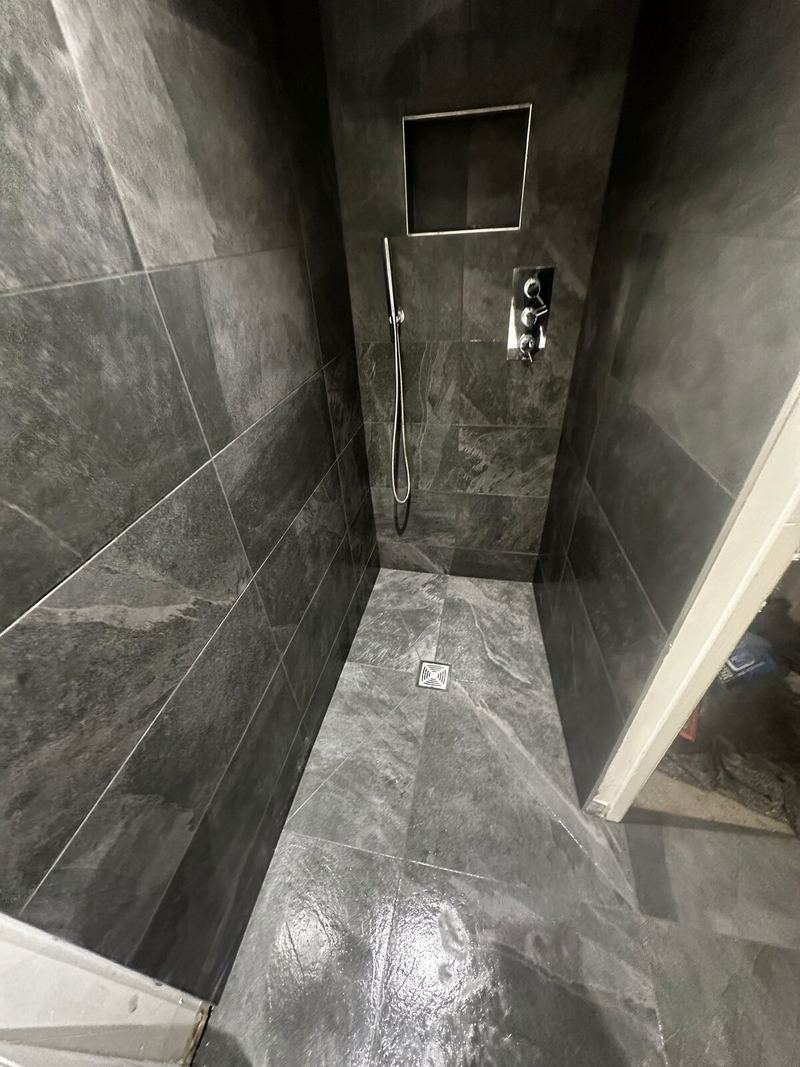 Walk-in wet room in slate-grey large-format tiles with a recessed niche